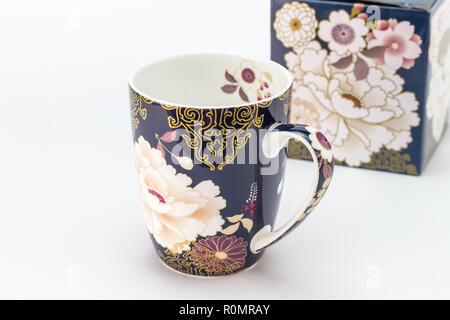 Tasse mug en porcelaine décoré avec des cadeaux / cup en premier plan et boîte-cadeau pour tasse en arrière-plan isolé sur fond blanc Banque D'Images