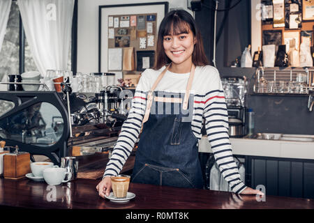 Asian female barista de porter un tablier jean place sa main sur le comptoir de bar et souriant au concept de service client,cafe,propriétaire démarrage d'entreprise. Banque D'Images