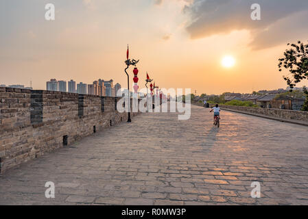 Xi'an, province du Shaanxi, Chine - Aug 8, 2018 : les touristes randonnée équestre location sur le mur de la ville au coucher du soleil Banque D'Images