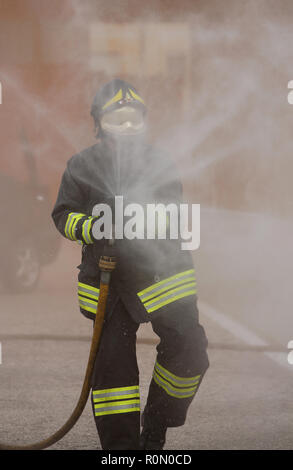 Italia, Italie - 10 mai 2018 : l'italien pompier avec casque et uniforme utilise l'incendie avec de la mousse au cours d'un exercice dans le service d'incendie Banque D'Images