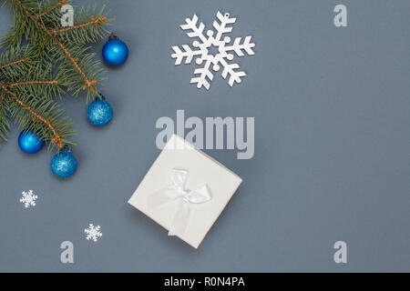 Décoration de Noël. Boîte cadeau, branches de sapins avec des boules de décoration, jouet snowflackes sur fond gris. Vue d'en haut. Carte de vœux de Noël concept Banque D'Images