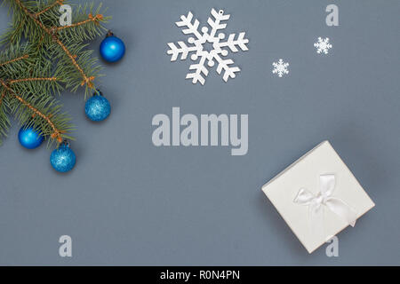 Décoration de Noël. Boîte cadeau, branches de sapins avec des boules de décoration, jouet snowflackes sur fond gris. Vue d'en haut. Carte de vœux de Noël concept Banque D'Images