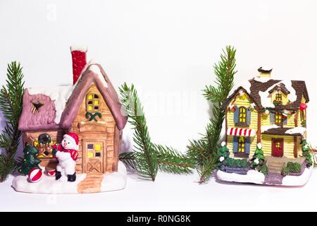 Deux belles maisons décorées du Nouvel An se tiennent sur un fond blanc, à côté d'une maison est un bonhomme. Banque D'Images