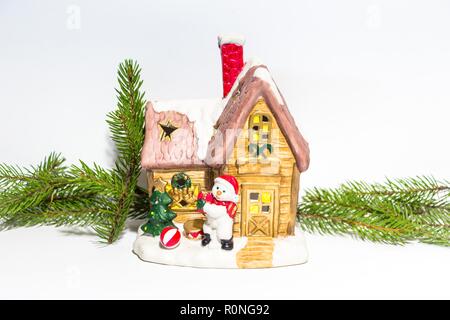 Belle maison du Nouvel An décorées sur un fond blanc, à côté d'une maison est un bonhomme. Autour de les maisons sont des branches de sapin. Banque D'Images