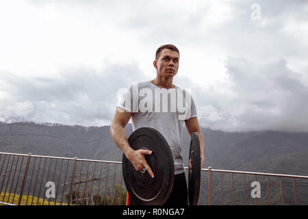 Athlète masculin Stong musculs pompage avec disques d'entraînement en plein air. Banque D'Images