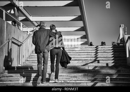 Photo en noir et blanc d'un mâle et femelle non identifiables en train de marcher en haut d'un escalier en béton à l'extérieur Banque D'Images