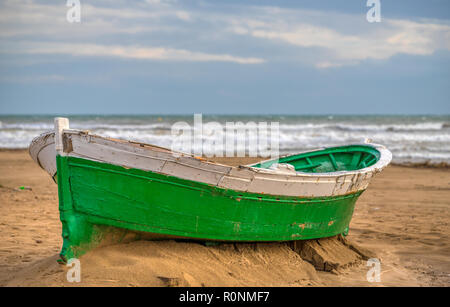 Un petit vert clair et blanc sur marron bateau en bois avec les vagues de sable et un ciel bleu et les nuages blancs dans l'arrière-plan Banque D'Images