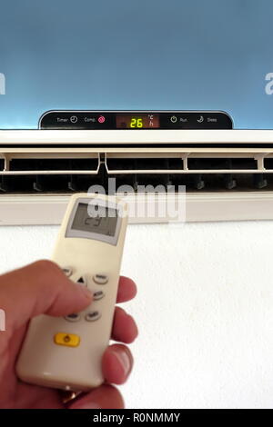 Quelqu'un la modification des paramètres d'un AC ou d'unité d'air conditionné avec télécommande - l'accent sur l'unité murale Banque D'Images