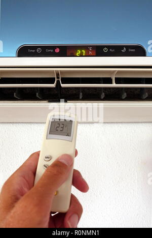 Quelqu'un la modification des paramètres d'un AC ou d'unité d'air conditionné avec télécommande - l'accent sur l'unité murale Banque D'Images
