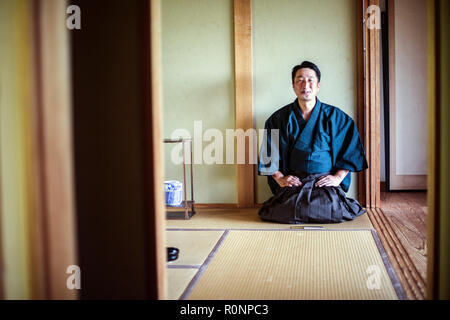 Kimono japonais homme portant à genoux sur marbre, sur un tatami au cours de cérémonie du thé. Banque D'Images