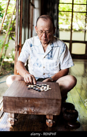 L'homme japonais assis sur le plancher sur porche de maison japonaise traditionnelle, à l'aller. Banque D'Images
