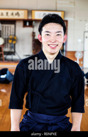 Le kendo japonais mâles fighter debout dans une salle de sport, smiling at camera. Banque D'Images