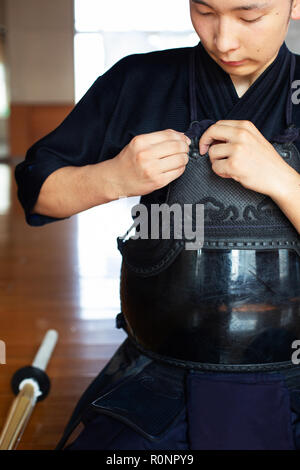 Le kendo japonais mâles fighter à genoux sur marbre, bouclant sa cuirasse. Banque D'Images