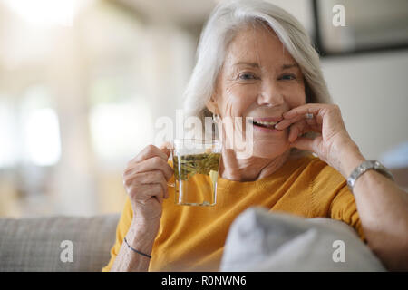 Belle femme senior à la maison avec une tasse de thé en feuilles Banque D'Images