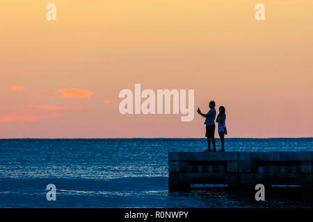 Couple qui se profilant selfies contre un ciel coucher de soleil orange sur le golfe du Mexique dans le sud-ouest de la Floride, États-Unis Banque D'Images