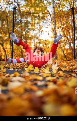 Garçon sautant sur un trampoline recouvert de feuilles d'automne, United States Banque D'Images