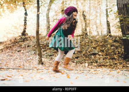 Un portrait d'un petit enfant fille courir en forêt en automne la nature. Banque D'Images