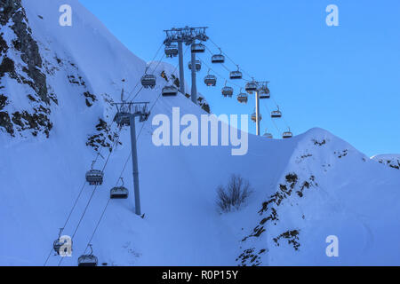 Skieurs et Surfeurs ride sur président téléskis à Gorki Gorod mountain ski resort à Sotchi, en Russie, sur fond de ciel bleu dans la soirée d'hiver ensoleillée da Banque D'Images