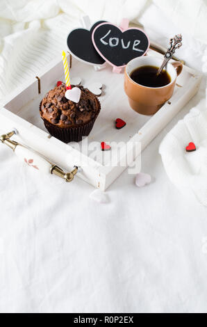 Muffins ou capkakes avec du chocolat et du café noir sur un plateau en bois au lit. Arrière-plan blanc. Un aliment sucré. Ambiance de fête copie espace télévision lay Banque D'Images