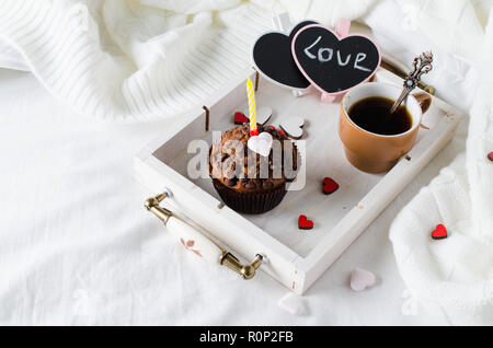 Muffins ou capkakes avec du chocolat et du café noir sur un plateau en bois au lit. Arrière-plan blanc. Un aliment sucré. Ambiance de fête copie espace télévision lay Banque D'Images