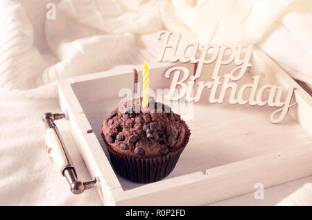 Anniversaire capkakes ou muffins au chocolat sur un plateau en bois au lit. Arrière-plan blanc. Un aliment sucré. Ambiance de fête copie espace télévision lay Banque D'Images