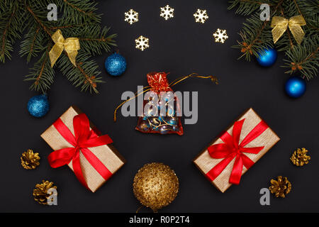 Décoration de Noël. Des boîtes-cadeaux, branches de sapins avec les cônes et boules de jouet sur fond noir. Vue d'en haut. Carte de vœux de Noël concept. Banque D'Images