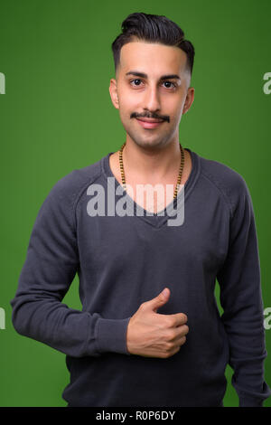 Beau jeune homme iranien avec moustache contre green backgroun Banque D'Images