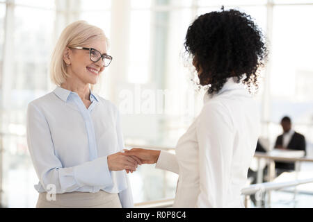 Smiling divers collègues de sexe féminin dans le couloir réunion handshake Banque D'Images