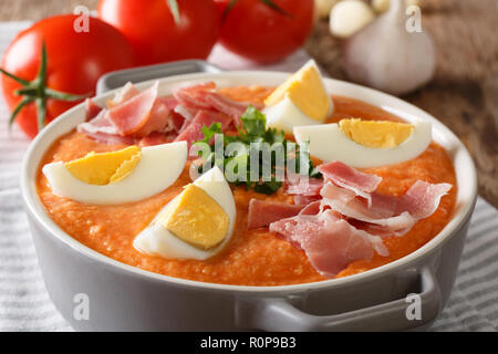 Soupe froide espagnol Antequera Porra fabriqué à partir de tomates, le poivre et l'ail servi avec des oeufs durs et du jambon dans une casserole sur la table horizontale. Banque D'Images