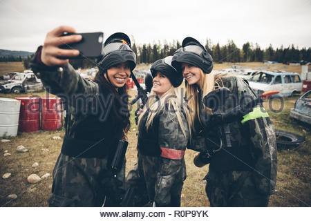 Les femmes amis paintball, en tenant au champ selfies