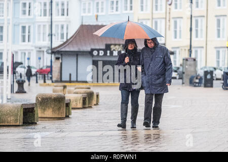 Aberystwyth, Pays de Galles, Royaume-Uni. 7 novembre, 2018. Météo France : Les gens marcher sous la pluie sur une très humide , mais doux, matin à Aberystwyth. Le Met Office a émis une alerte jaune pour la pluie et les inondations couvrant une grande partie de l'ouest du pays de Galles et du sud ce matin, avec un avertissement supplémentaire pour plus de pluie et de forts coups de vent émis pour la même zone le vendredi aussi. Crédit photo : Keith Morris/ Alamy Live News Banque D'Images