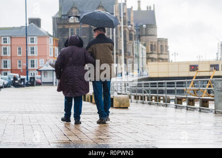 Aberystwyth, Pays de Galles, Royaume-Uni. 7 novembre, 2018. Météo France : Les gens marcher sous la pluie sur une très humide , mais doux, matin à Aberystwyth. Le Met Office a émis une alerte jaune pour la pluie et les inondations couvrant une grande partie de l'ouest du pays de Galles et du sud ce matin, avec un avertissement supplémentaire pour plus de pluie et de forts coups de vent émis pour la même zone le vendredi aussi. Crédit photo : Keith Morris/ Alamy Live News Banque D'Images