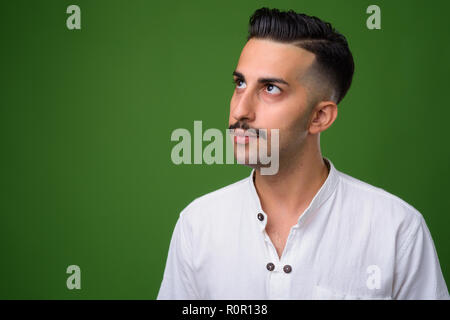 Beau jeune homme iranien avec moustache contre green backgroun Banque D'Images