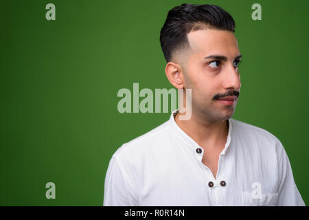 Beau jeune homme iranien avec moustache contre green backgroun Banque D'Images