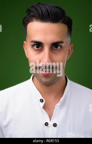 Beau jeune homme iranien avec moustache contre green backgroun Banque D'Images