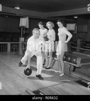 Bowling dans le 1950s. Un homme lance le bowling et trois jeunes femmes se tiennent à côté et regardent. Elles sont vêtues de jupes et de pulls à rayures courtes. Les trois filles sont toutes des actrices de théâtre : Ingrid Björk, UllaCarin Rydén et BRITA Ulfberg. Les spectacles Ewert Ekström les instruit dans le bowling. Il était joueur professionnel de bowling en 1930s et est actuellement instructeur et propriétaire du club de bowling. 1950 Suède photo Kristoffersson réf. AY36-3 Banque D'Images