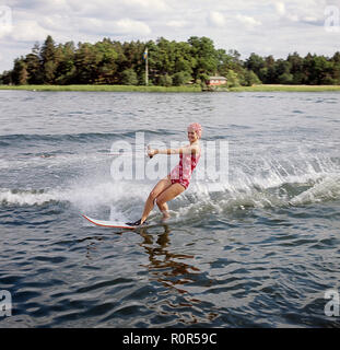 Le ski nautique dans les années 60. Une jeune femme en maillot de bain à motifs passe le photographe sur son waterskis. Elle a un bonnet de sur. La Suède 1946 Photo Kristoffersson ref CV12-7