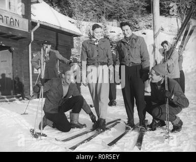 L'hiver dans les années 40. Un jeune couple sur ski holiday obtient de l'aide pour attacher vos skis par Stig skieur record du monde Lindgård distance runner Roland Sundin. 1947 Suède Åre Banque D'Images