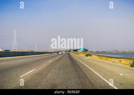 Voyageant sur Dumbarton bridge vers l'est de la baie de San Francisco ; la fumée et de la pollution dans l'air à proximité de friches, Silicon Valley, Californie Banque D'Images