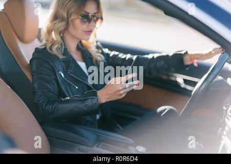 Photo de la fille du pilote avec téléphone en mains sitting in car Banque D'Images