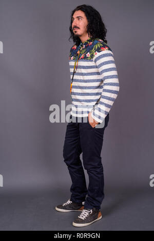 Bel homme avec des cheveux bouclés et d'une moustache contre gray backgroun Banque D'Images