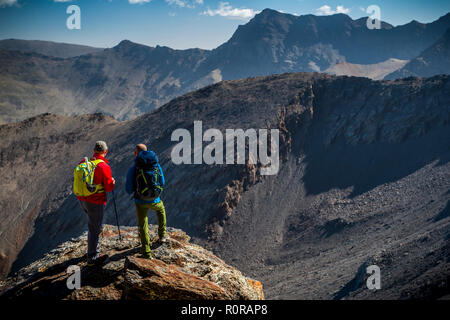 Vue arrière de deux voyageurs masculins debout sur rock et en regardant les montagnes magnifiques sur belle journée ensoleillée en Sierra Nevada, Granada, Espagne Banque D'Images