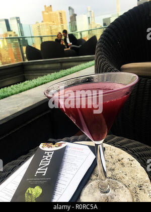 Fruit martini à Press Lounge, avec ad pour l'impression. Restaurant sur la table et de couple à l'écoute de l'autre/Manhattan skyline en arrière-plan, New York, NY Banque D'Images