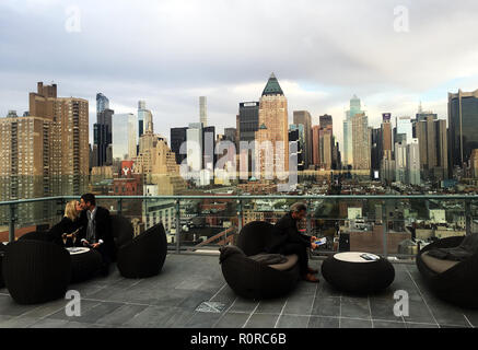 Jeune couple partager un baiser et champagne au Salon Presse bar sur le toit en face de l'horizon de Manhattan en début de soirée, New York, NY Banque D'Images