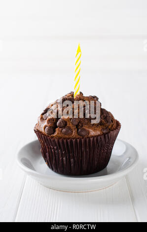 Anniversaire capkakes ou muffins au chocolat et des bougies sur une table en bois blanc. Arrière-plan blanc. Un aliment sucré. Ambiance de fête copie espace télévision lay Banque D'Images