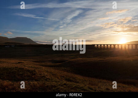 Un Northern rail class 158 sprinter train entre Ribblehead viaduc et Ingleborough dans le Yorkshire Dales au coucher du soleil faire une silhouette Banque D'Images