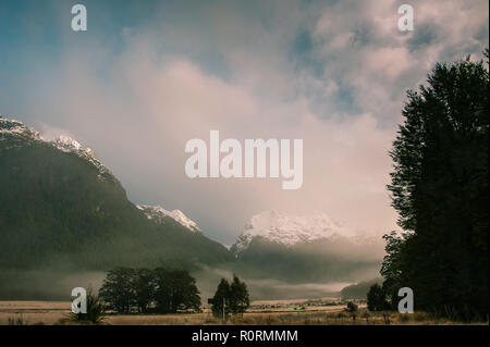 Lever de soleil à Fiordland, Nouvelle-Zélande. Les brouillards accrocher au-dessus de la vallée, avec une montagne et ciel nuageux fond. Banque D'Images