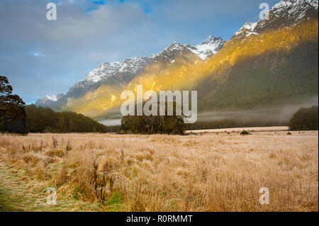 Lever de soleil à Fiordland, Nouvelle-Zélande. Les brouillards accrocher au-dessus de la vallée, avec une montagne et ciel nuageux fond. Banque D'Images