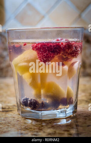 Infusé fruits seltzer l'eau pétillante avec les framboises et les bleuets d'ananas sur comptoir de cuisine en marbre Banque D'Images