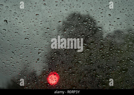 Gouttes de pluie sur une fenêtre d'une voiture, debout devant un feu de circulation Banque D'Images